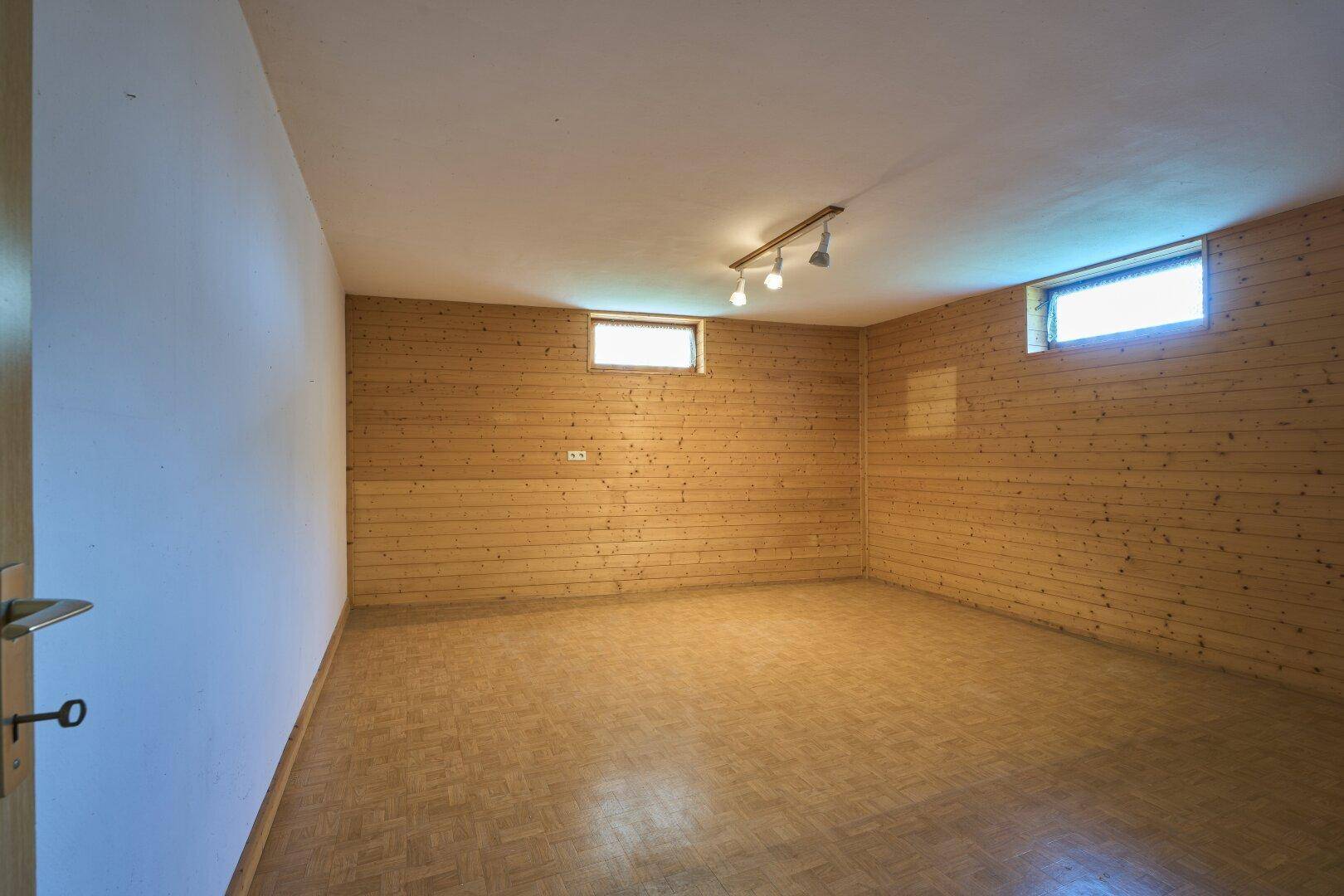 Ausgebauter Kellerraum mit Holzverkleidung an den Wänden und kleinem Fenster.