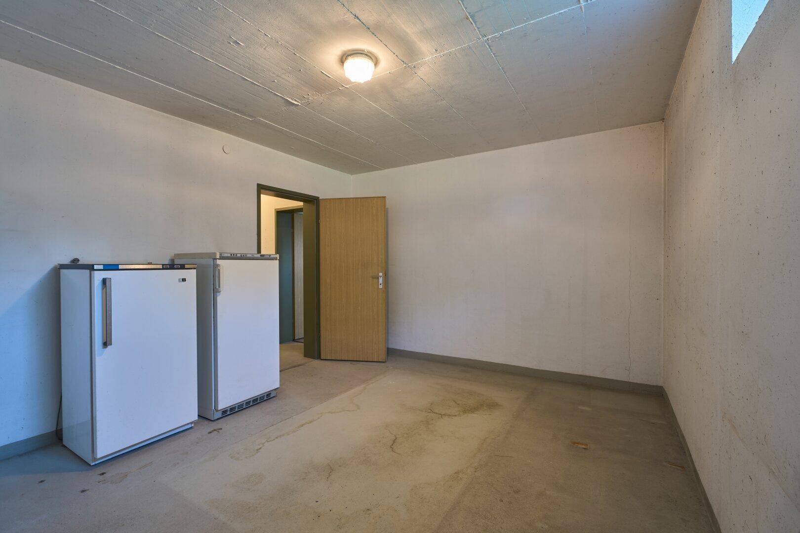 Kellerraum mit zwei Gefrierschränken und Betonboden, ideal als Vorratsraum.
