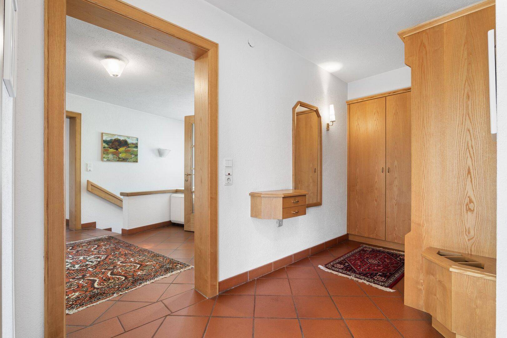 Geräumiger Flur mit Terrakottafliesen und praktischen Holz-Einbauschränken.