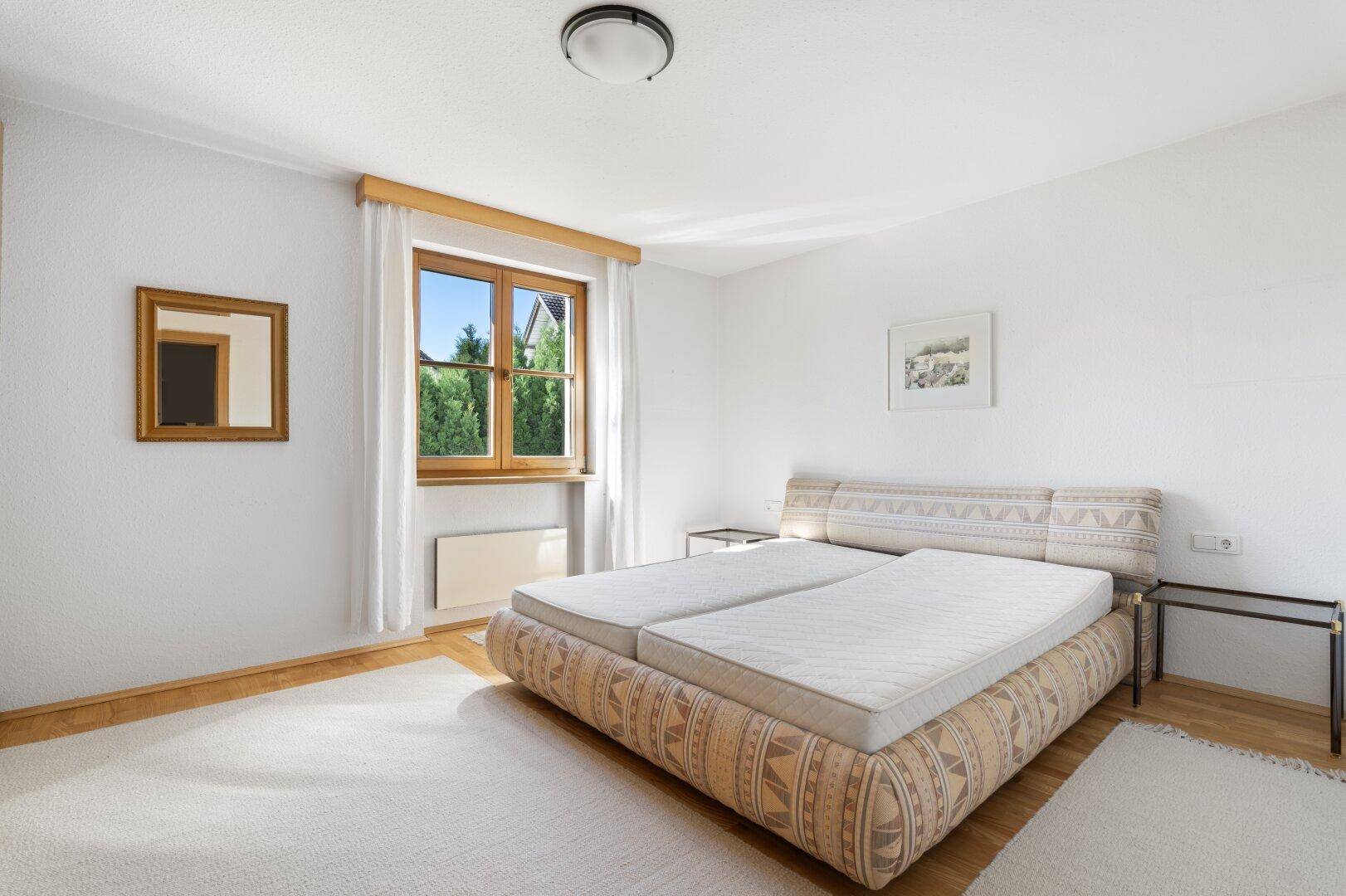 Schlafzimmer mit Teppichboden, einem bequemen Bett und Fenster für Tageslicht.