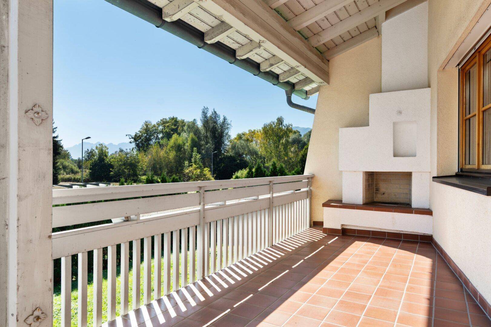 Überdachter Balkon mit Terrakottafliesen, Außenkamin und weitem Blick in die Natur.