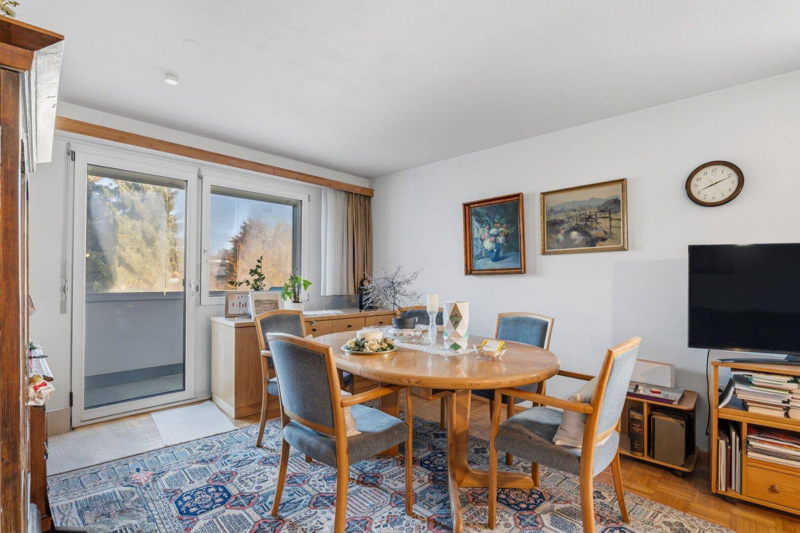 Essbereich mit rundem Holztisch, Stühlen und Zugang zu einem Balkon.