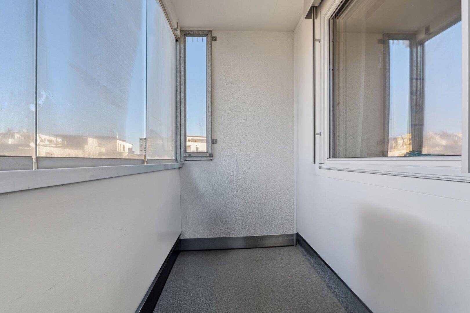 Verglaster Balkon mit hellem Boden und weitem Blick auf die Umgebung.