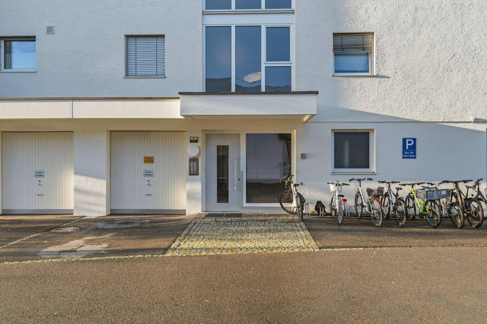 Eingangsbereich des Gebäudes mit Garagen, Fahrradstellplätzen und Parkmöglichkeiten.
