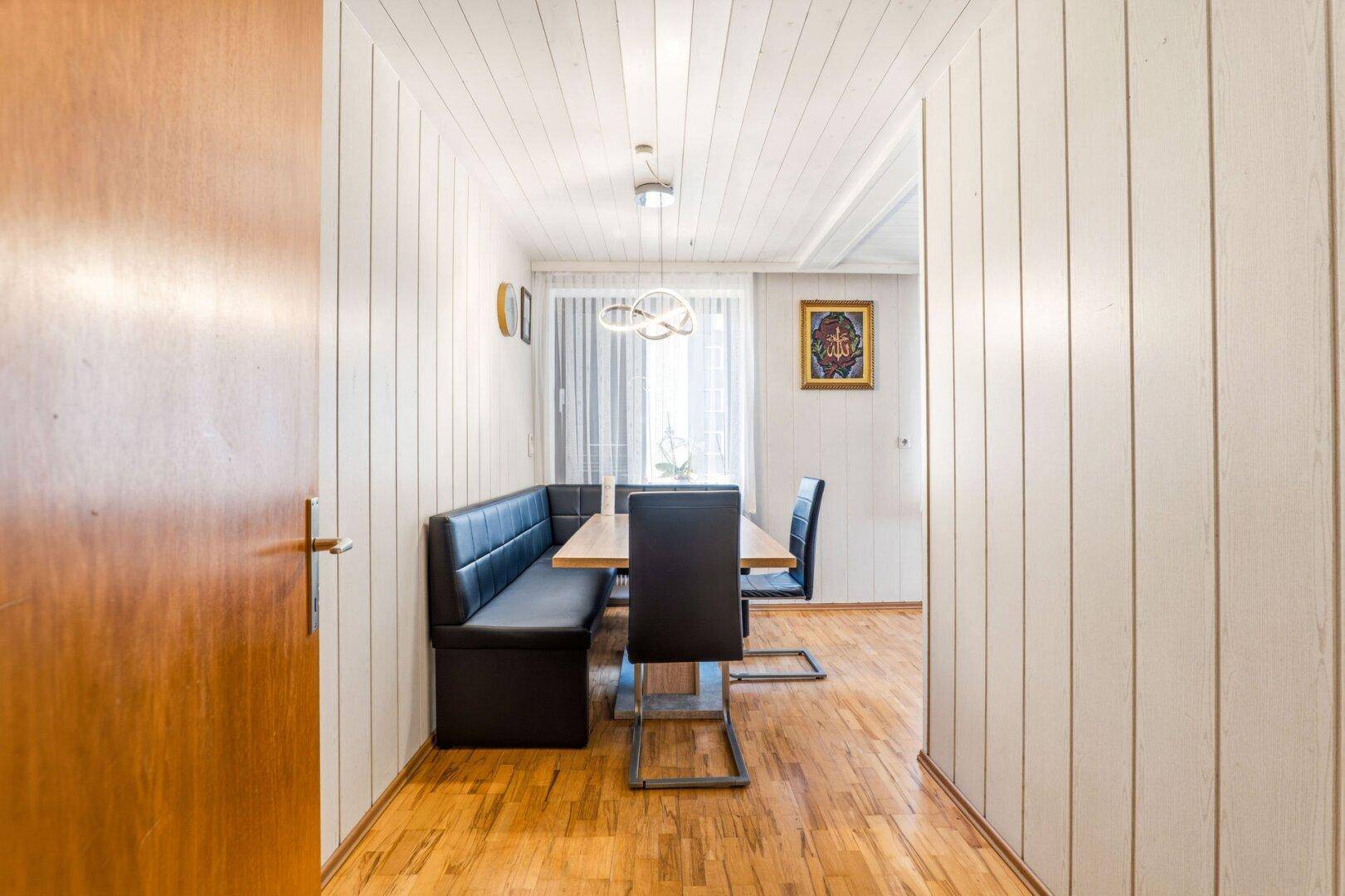 Gemütlicher Essbereich mit Holzboden, holzvertäfelten Wänden und Decke sowie einem modernen Esstisch.