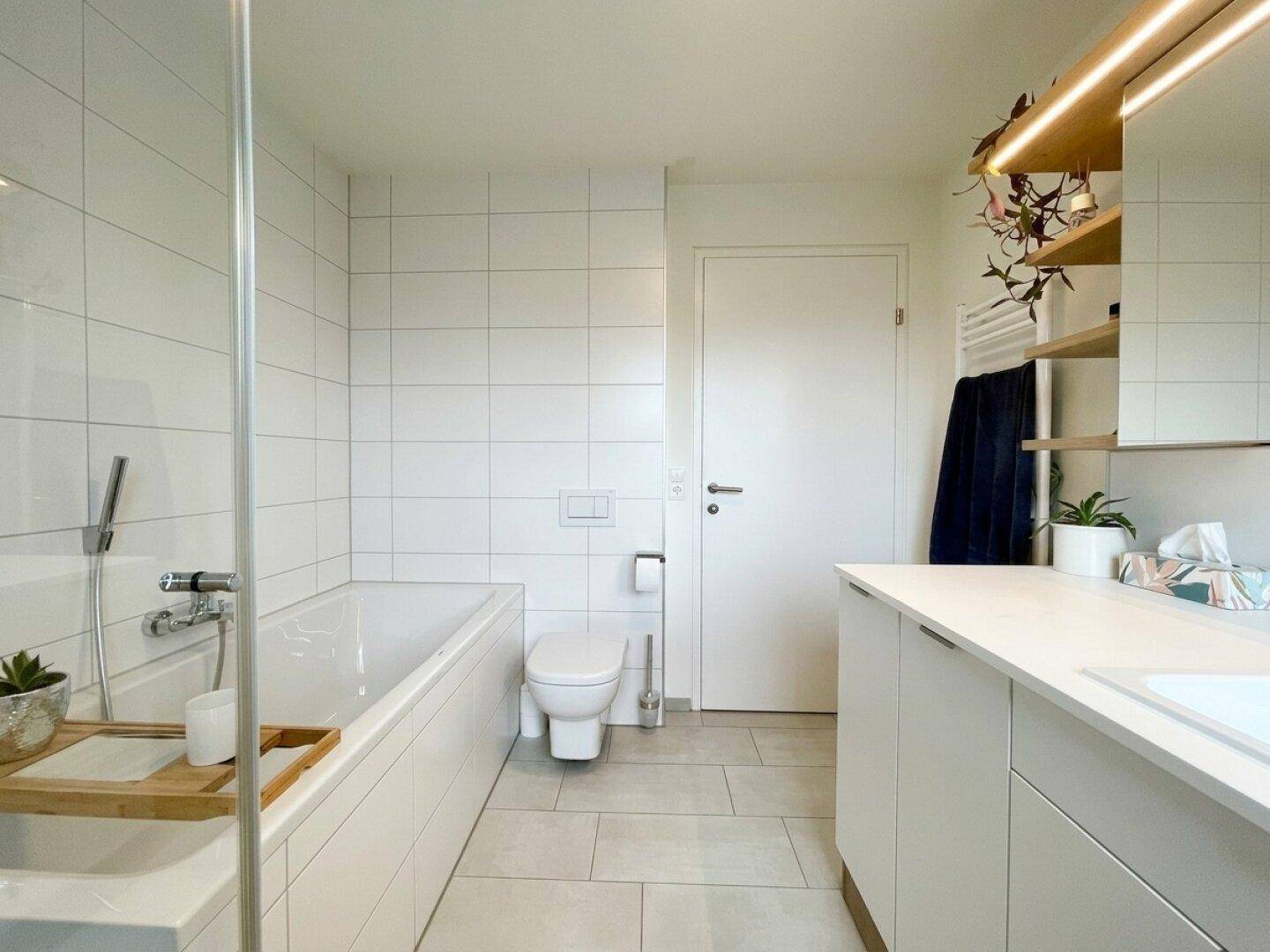 Helles Badezimmer mit Badewanne, wandhängendem WC und modernem Waschtischbereich.