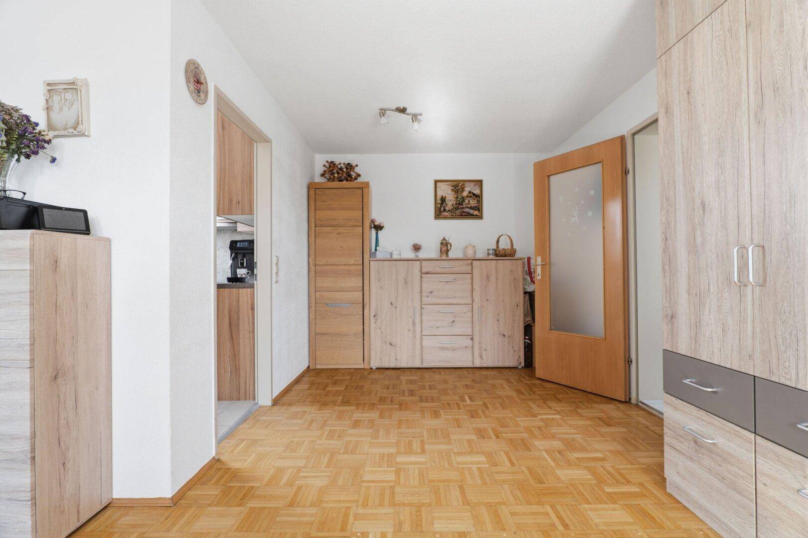 Heller Flur mit Parkettboden und praktischen Holzschränken, verbindet die Räume.