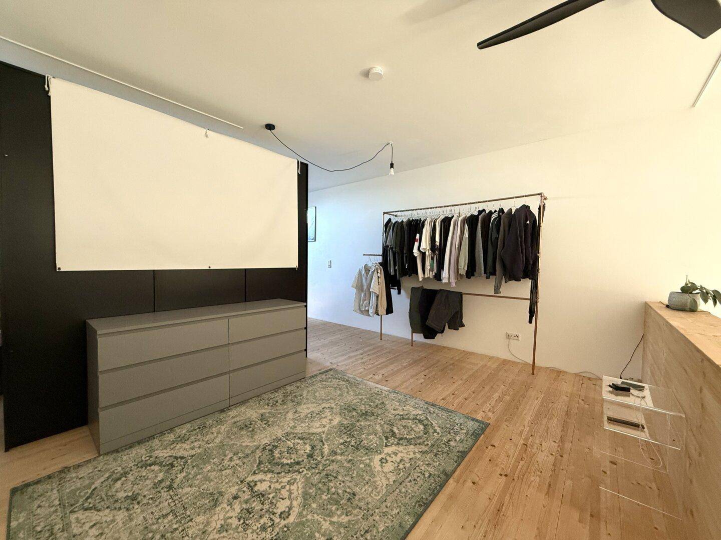 Schlafbereich auf der Galerie mit Holzboden, Kommode und offener Kleiderstange.