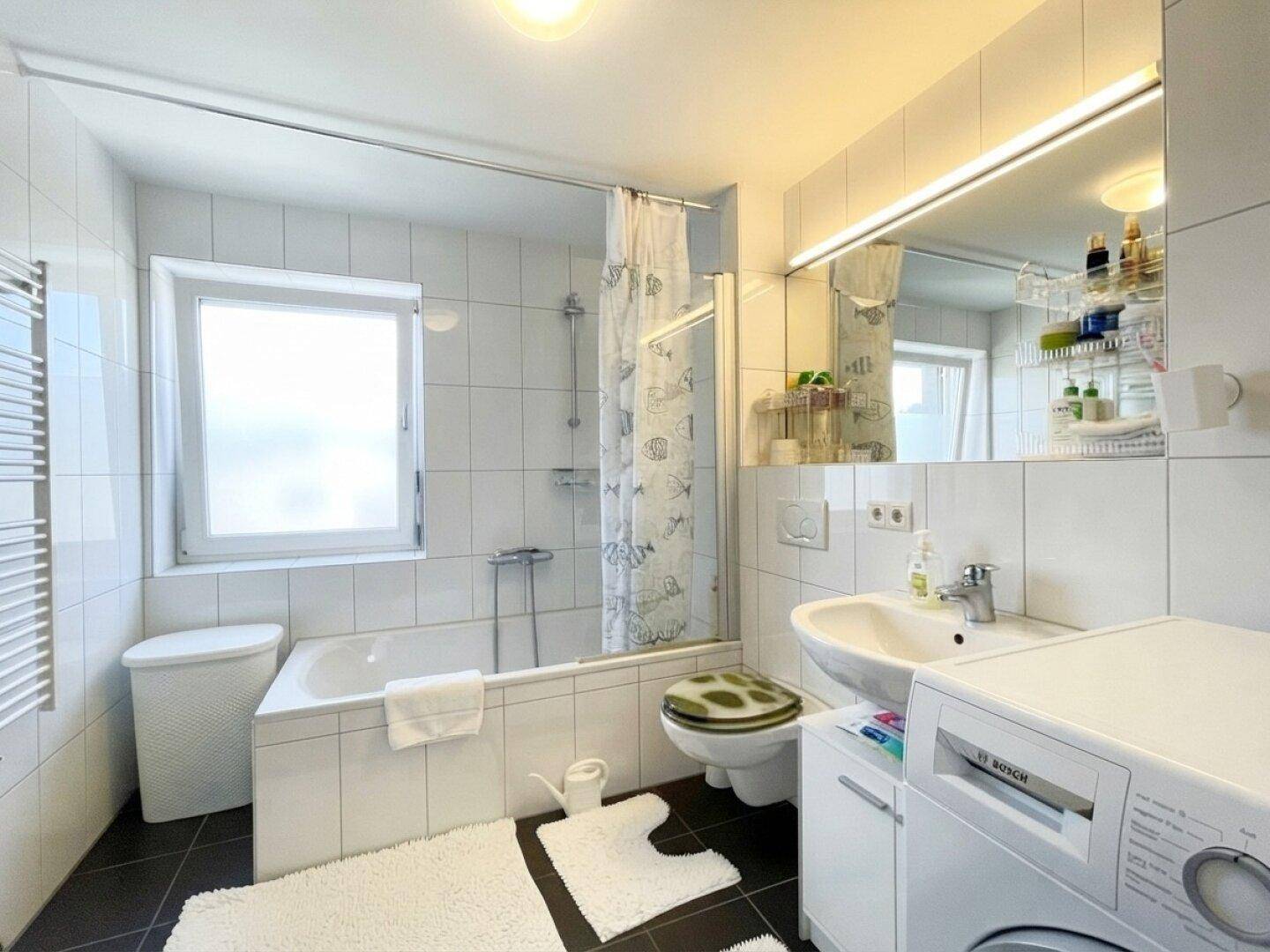 Funktionales Badezimmer mit Badewanne, Dusche und Waschmaschine.