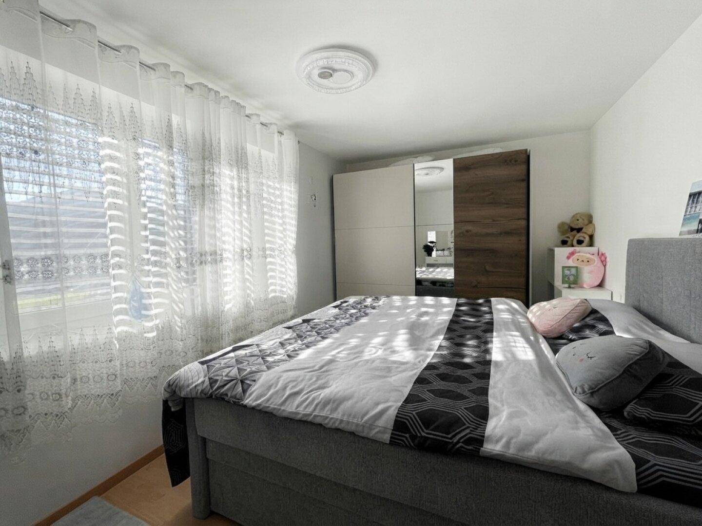 Gemütliches Schlafzimmer mit großem Bett, Kleiderschrank und viel Tageslicht.