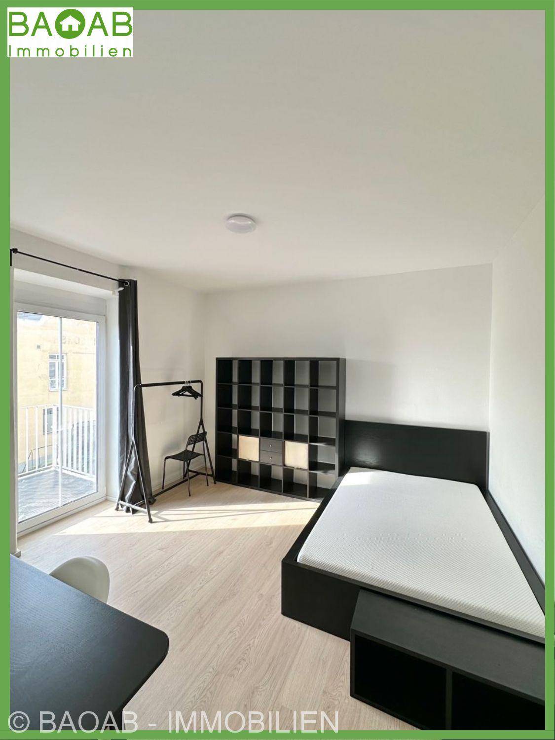 Schlafzimmer mit modernem Bett, Holzfußboden und direktem Zugang zu einem kleinen Balkon.
