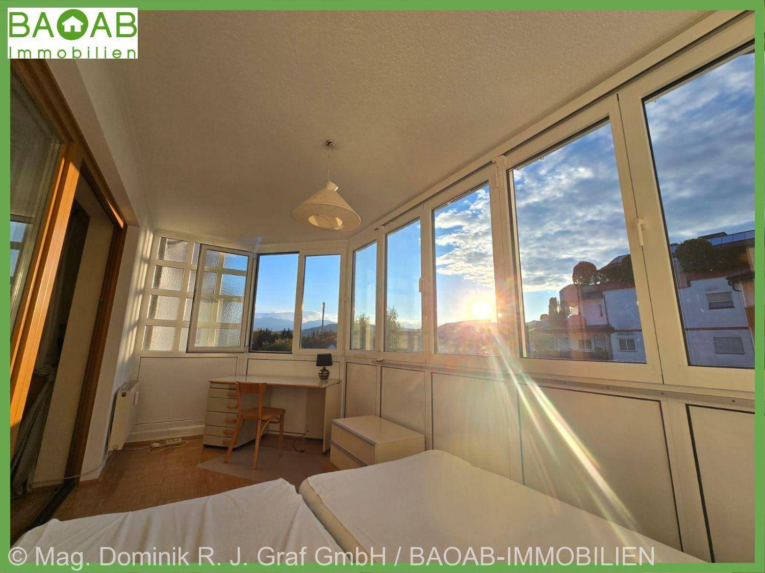 Schlafzimmer mit großen Fenstern, die viel Sonnenlicht hereinlassen und einen weiten Ausblick bieten.