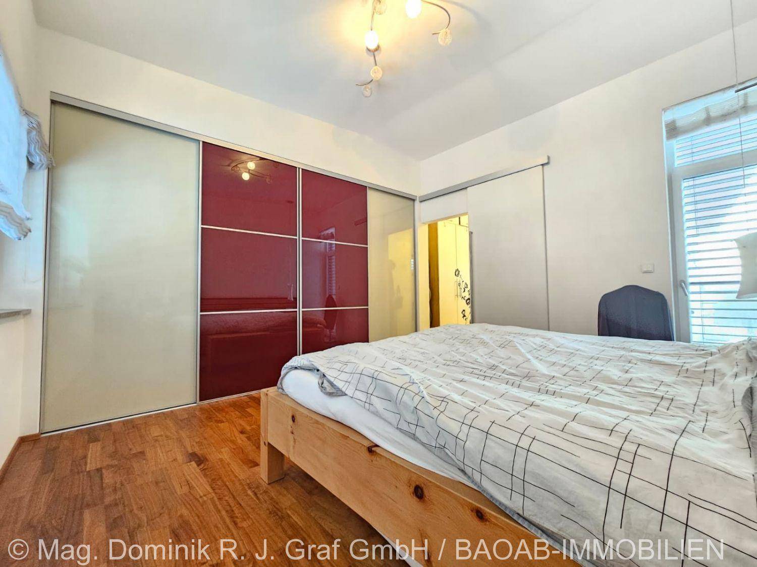 Schlafzimmer mit Holzboden und großen, modernen Einbauschränken mit Schiebetüren.