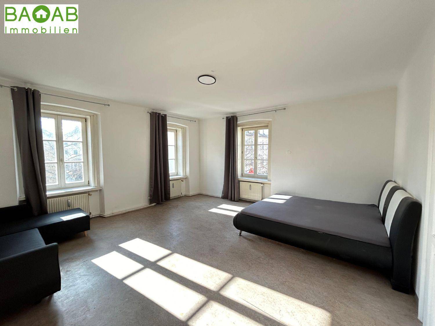 Helles Schlafzimmer mit großen Fenstern, Heizkörpern und viel natürlichem Licht auf dem Boden.