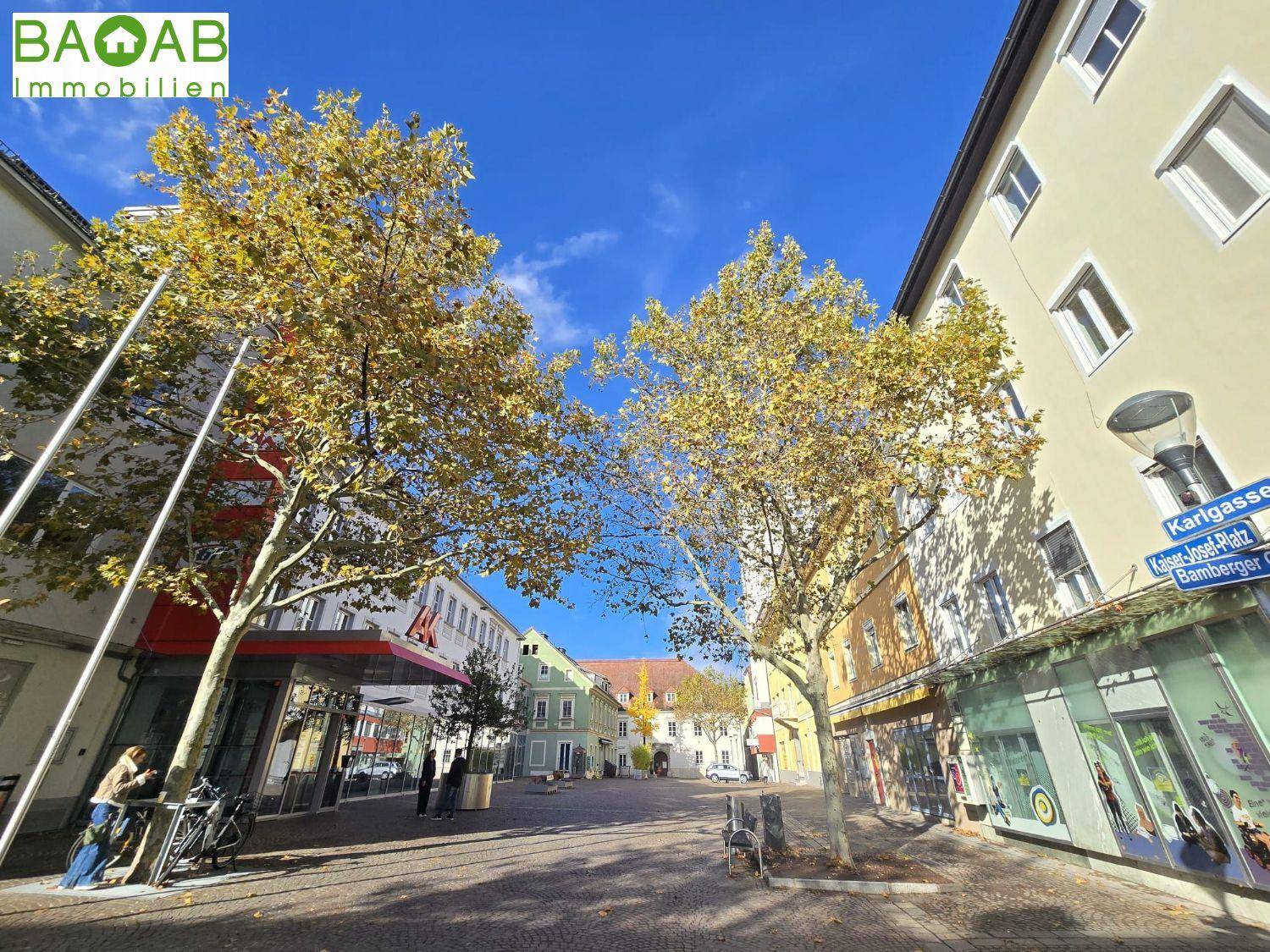 Herbstliche Straßenszene in der Stadt mit bunten Bäumen und historischen Gebäuden unter blauem Himmel.