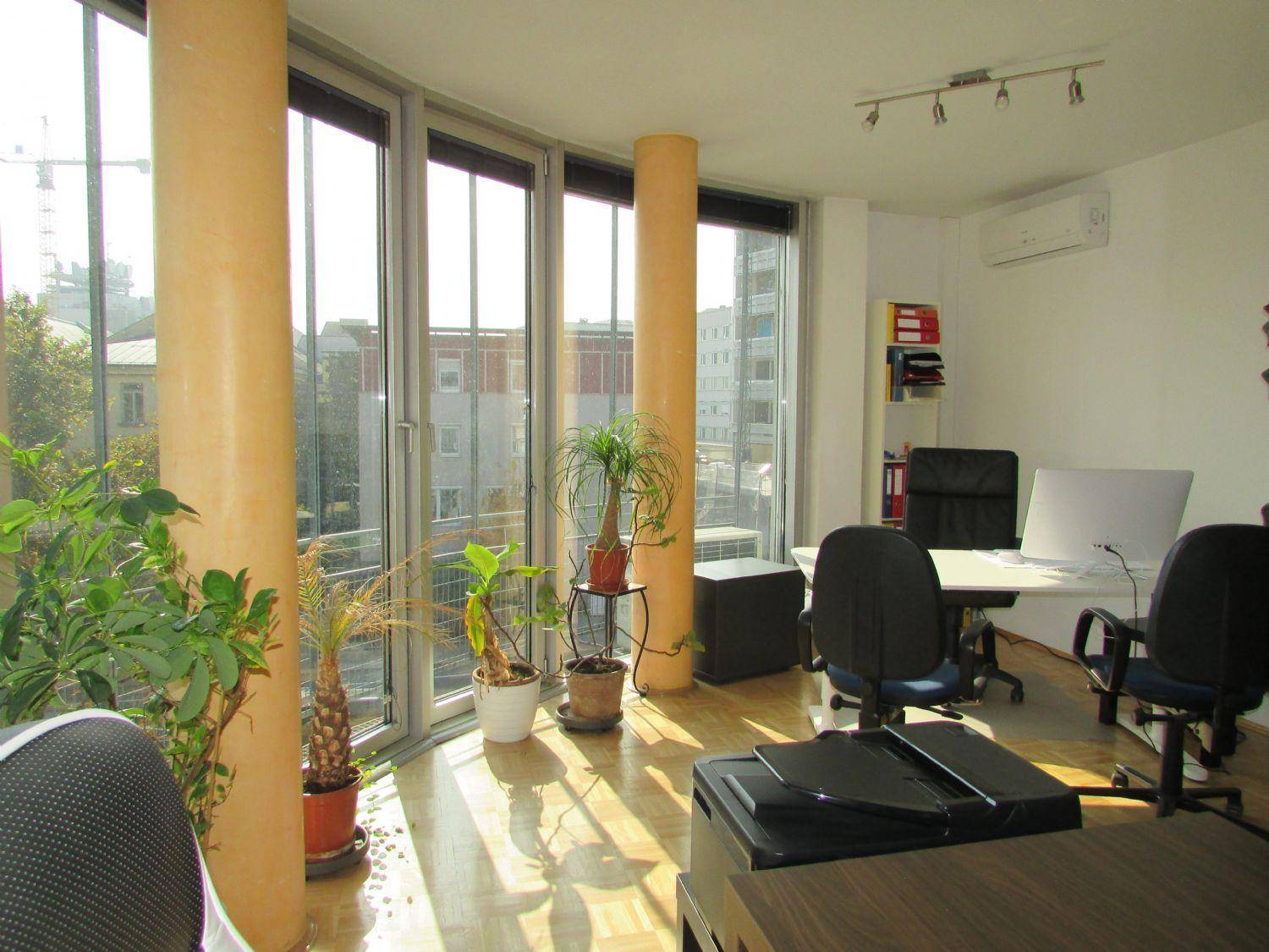 Geräumiges Büro mit großen, gebogenen Fenstern, die viel Tageslicht hereinlassen und einen Stadtblick bieten.