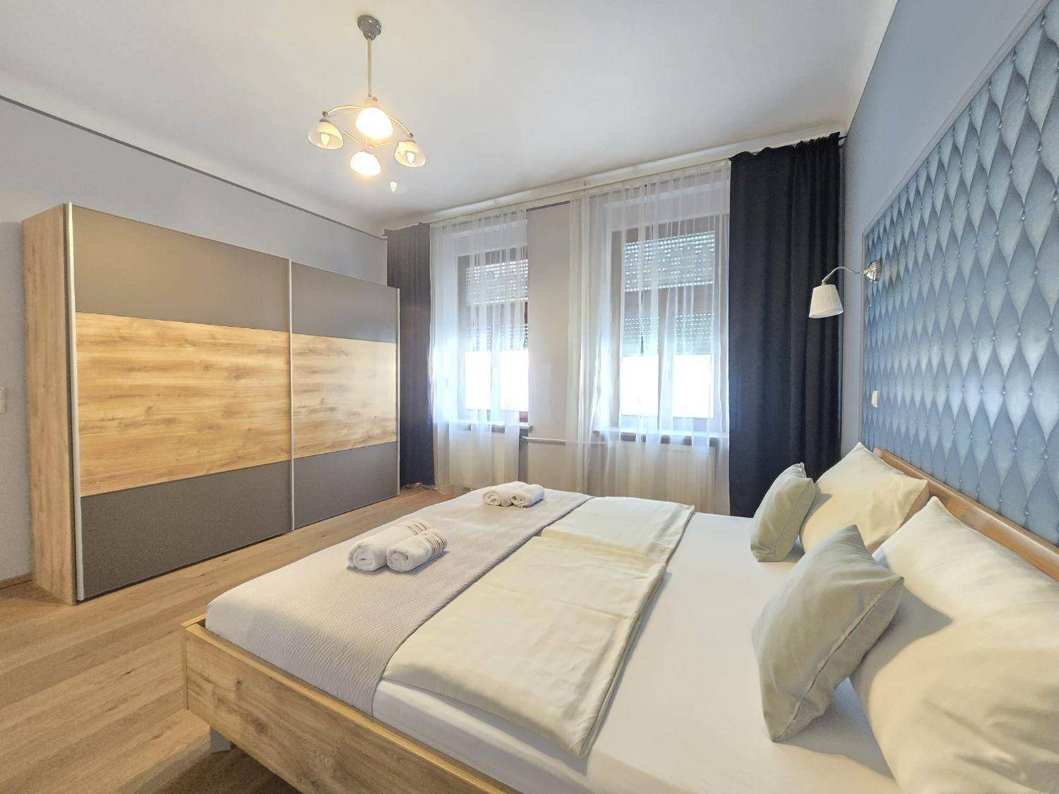 Modernes Schlafzimmer mit großem Schiebetürenschrank, Holzplankenboden und viel Tageslicht.
