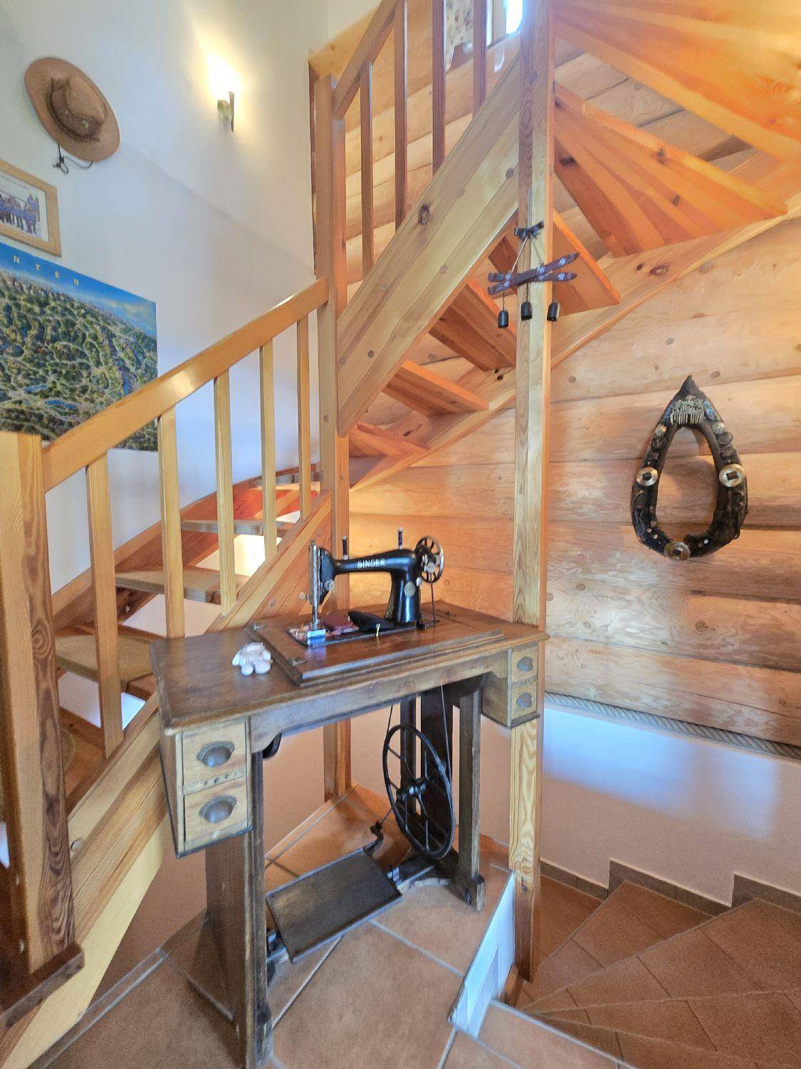 Holztreppe mit traditioneller Nähmaschine als Dekoration in einem rustikalen Ambiente.