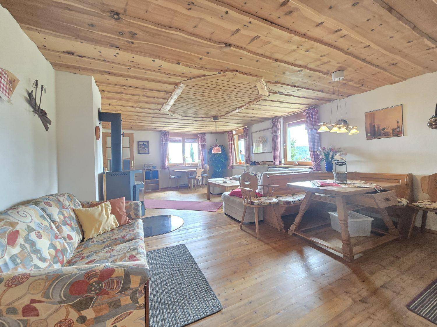 Rustikaler Wohnbereich mit Holzbalkendecke, Kaminofen und traditionellen Möbeln.