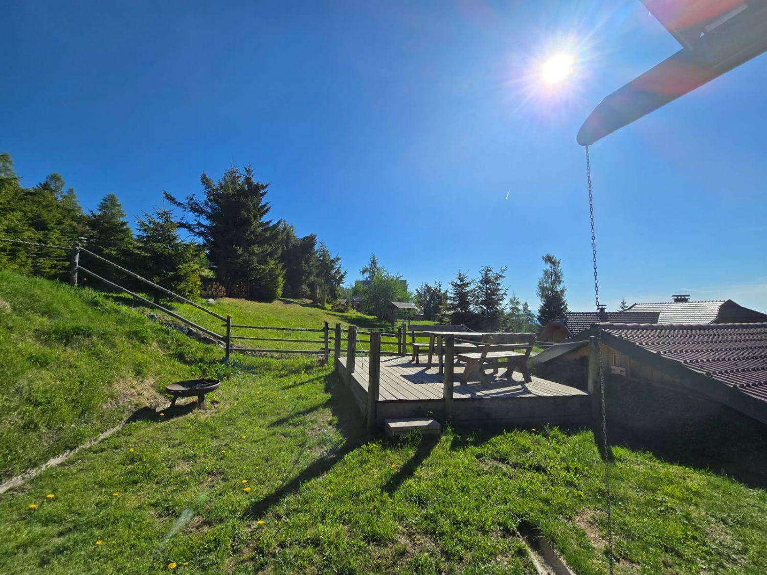 Sonnige Holzterrasse mit Sitzgelegenheiten und weitem Blick in die grüne Landschaft.