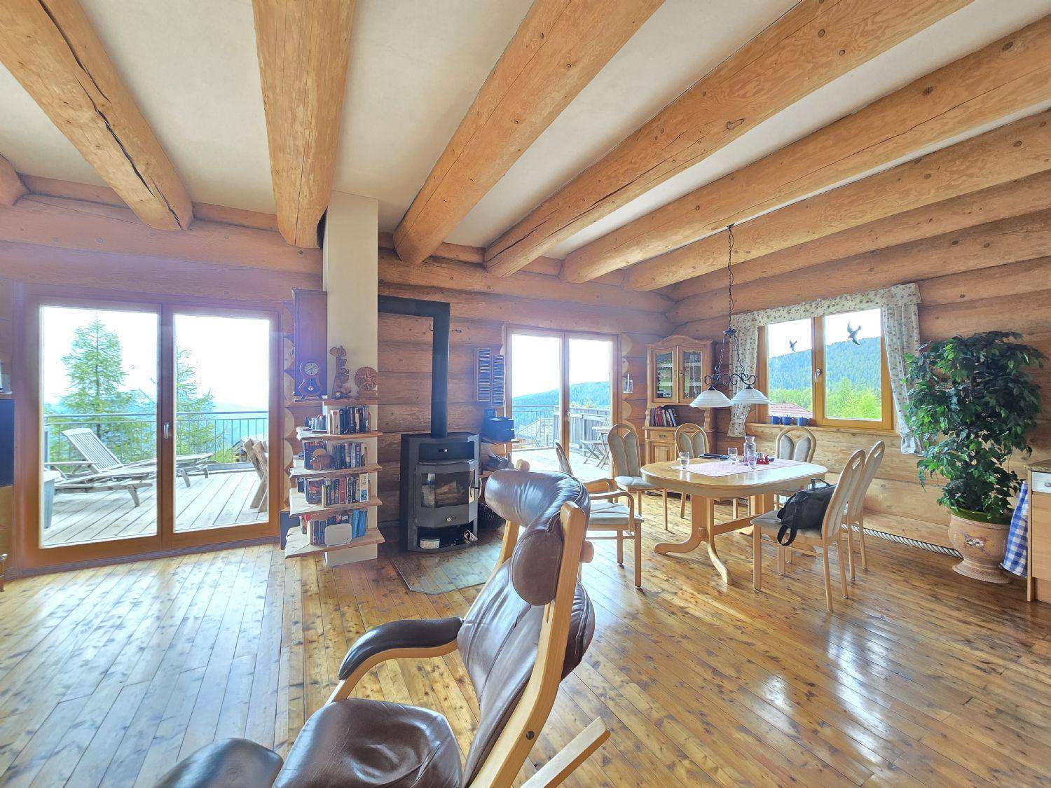 Gemütlicher Wohn- und Essbereich im alpinen Stil mit Kaminofen und Zugang zur Terrasse.