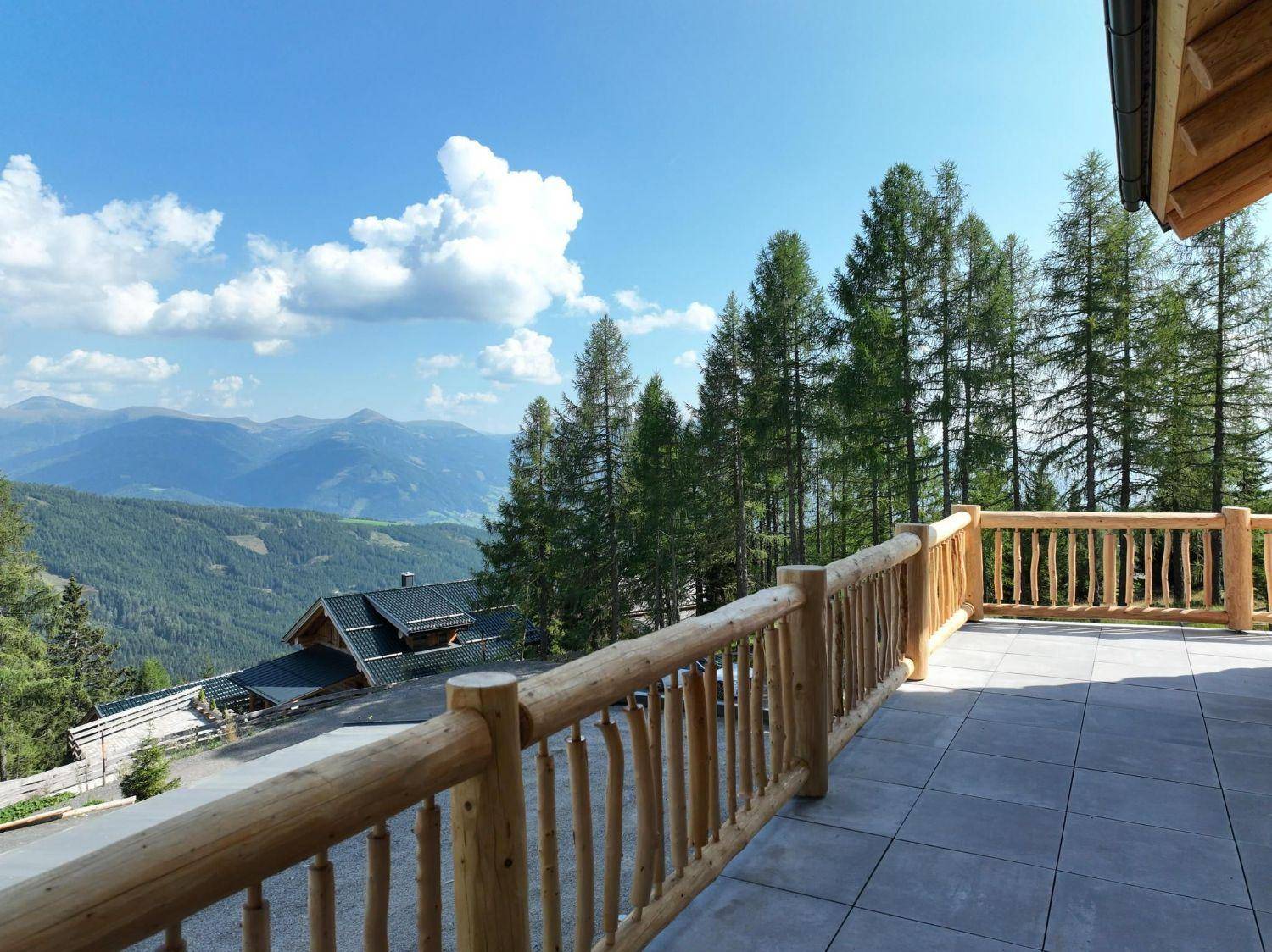 Geräumige Terrasse mit rustikalem Holzgeländer und weitem Panoramablick auf die umliegenden Berge.