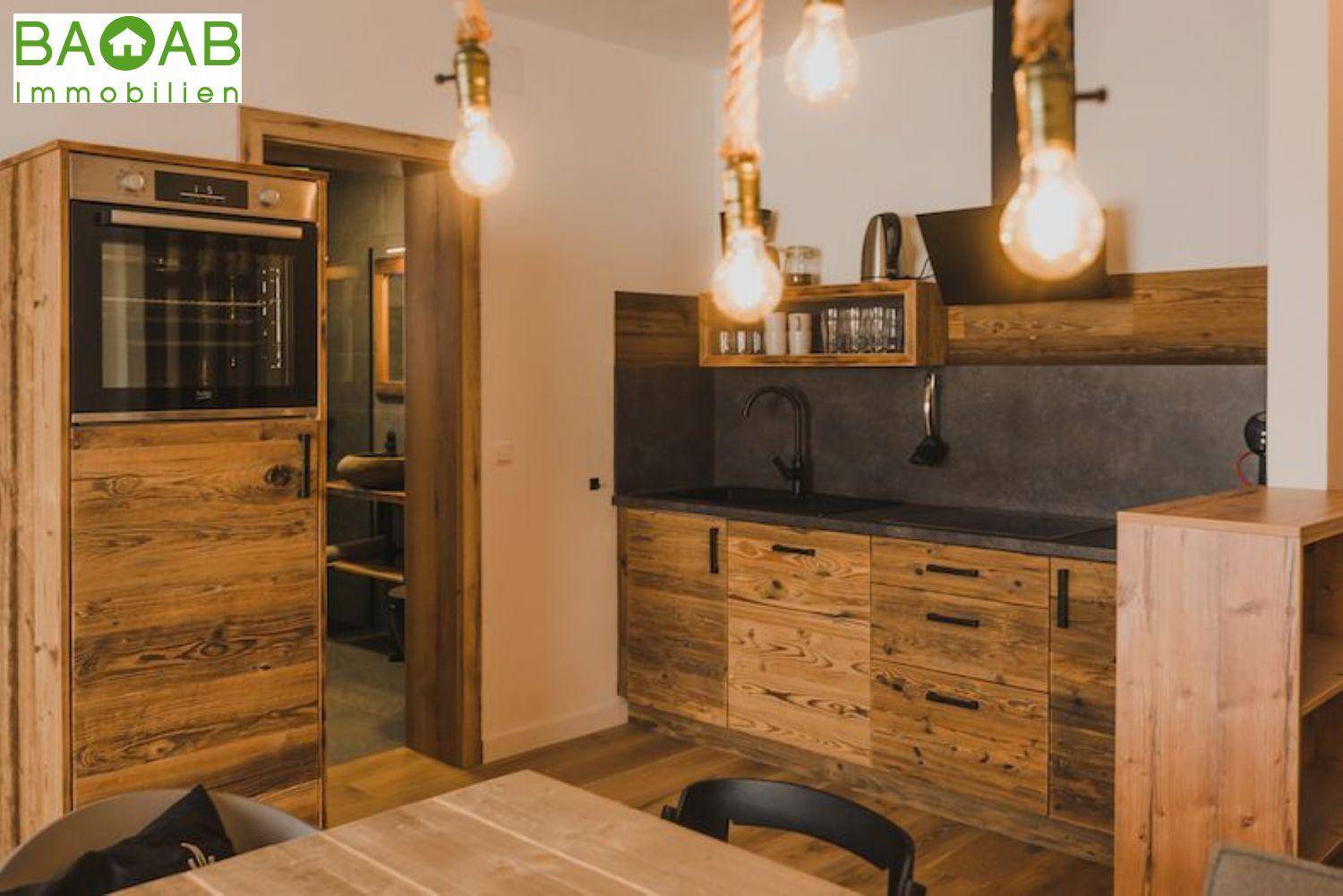 Funktionale Küche mit Holzelementen, Einbauofen und Zugang zu einem angrenzenden Raum.