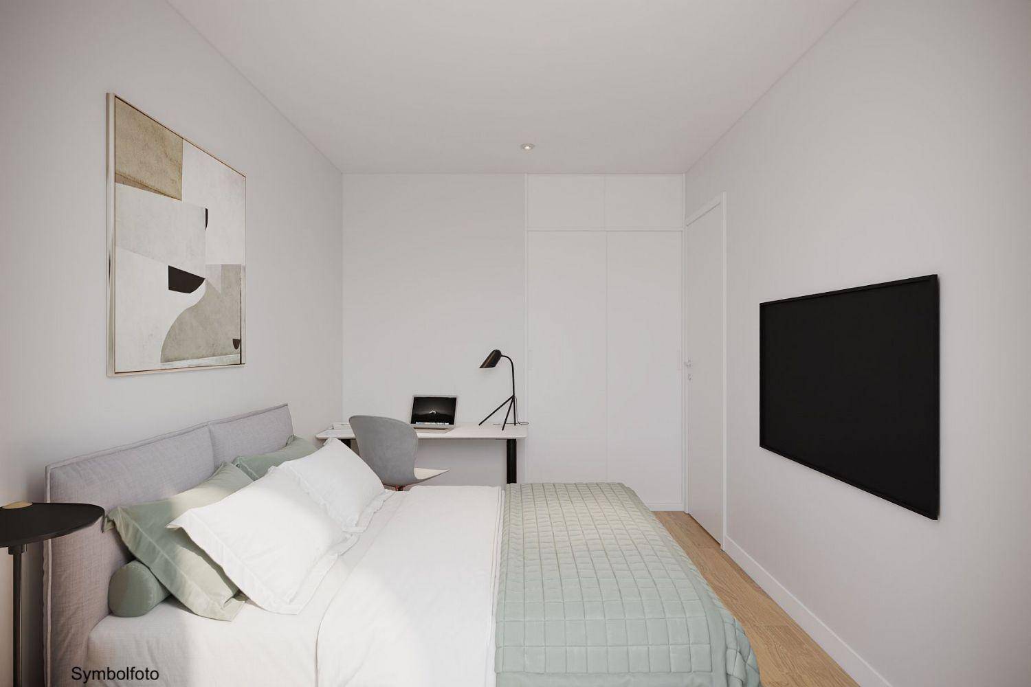 Modernes Schlafzimmer mit Doppelbett, Schreibtisch und minimalistischer Einrichtung in hellen Farben.