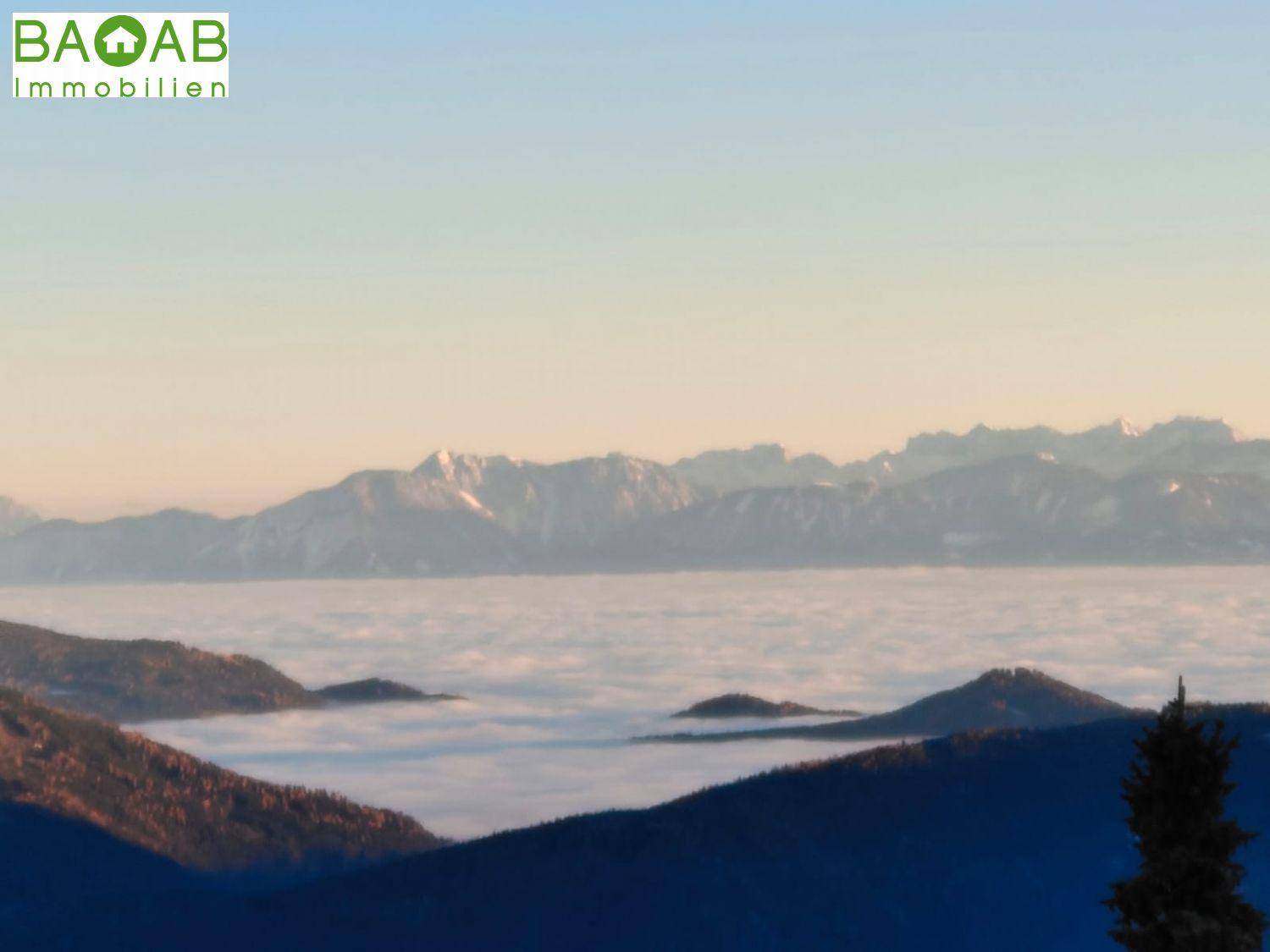 Malerischer Blick auf eine Bergkette mit Nebelmeer in den Tälern bei Sonnenaufgang oder -untergang.