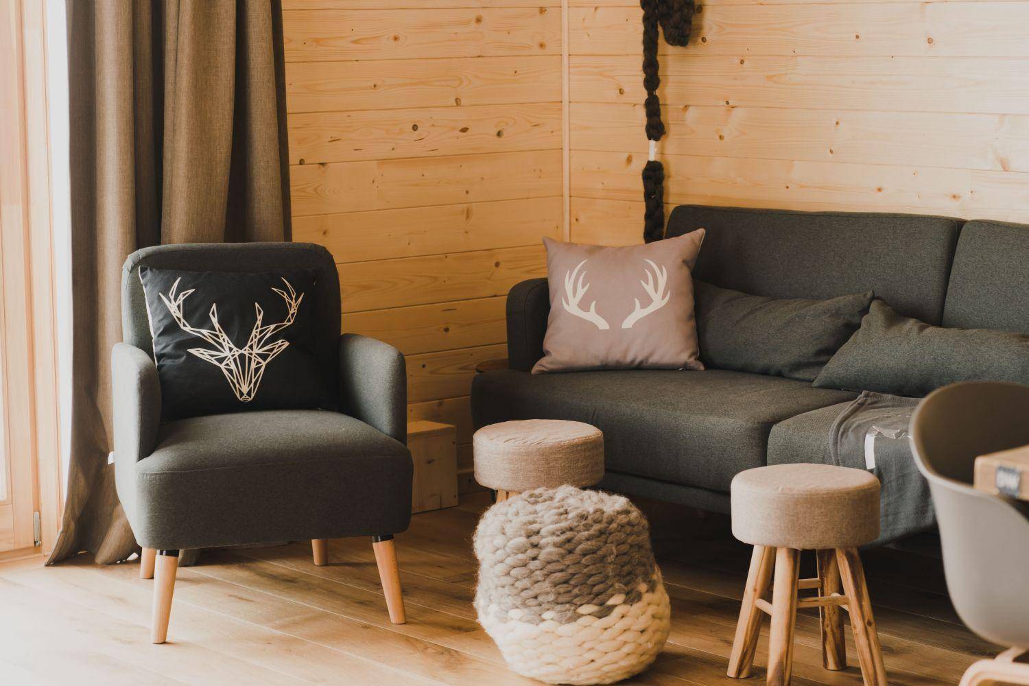 Gemütliche Sitzecke mit dunklem Sofa, Holzwänden und alpinen Dekorationselementen.