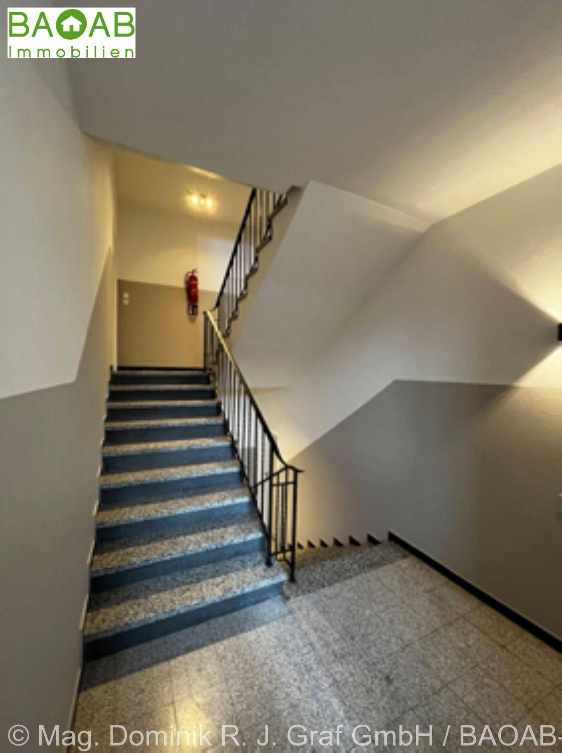 Treppenhaus mit Terrazzoboden und Metallgeländer, das die verschiedenen Etagen verbindet.