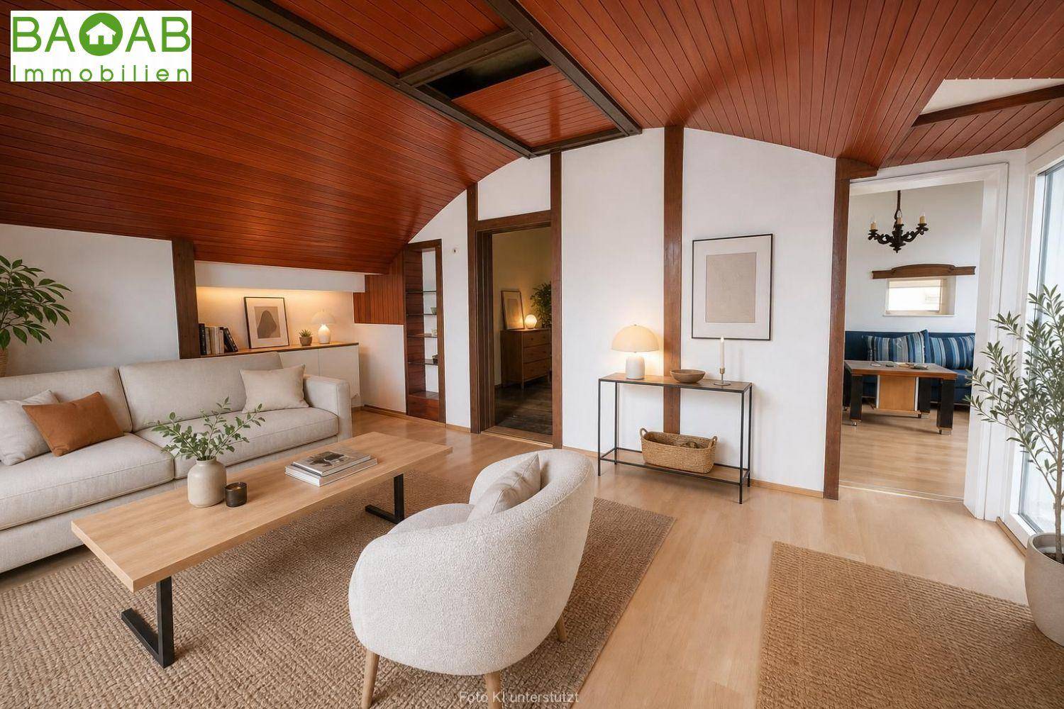 Gemütlicher Wohnbereich mit Holzbalkendecke, hellem Sofa und Zugang zu weiteren Räumen.
