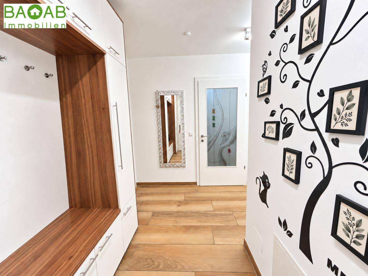 Heller Flur mit integrierter Garderobe, Spiegel und dekorativer Wandgestaltung, ausgestattet mit Holzboden.