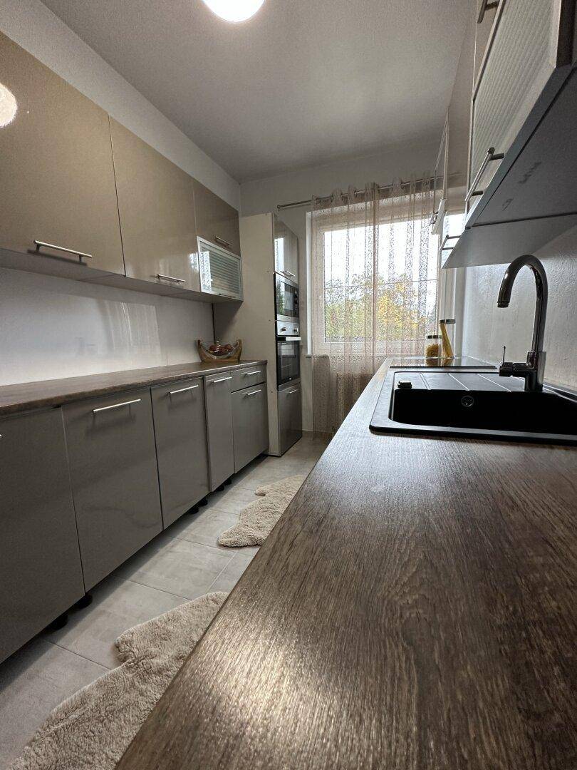 Detailansicht der modernen Küche mit Holzarbeitsplatte und Spülbecken.