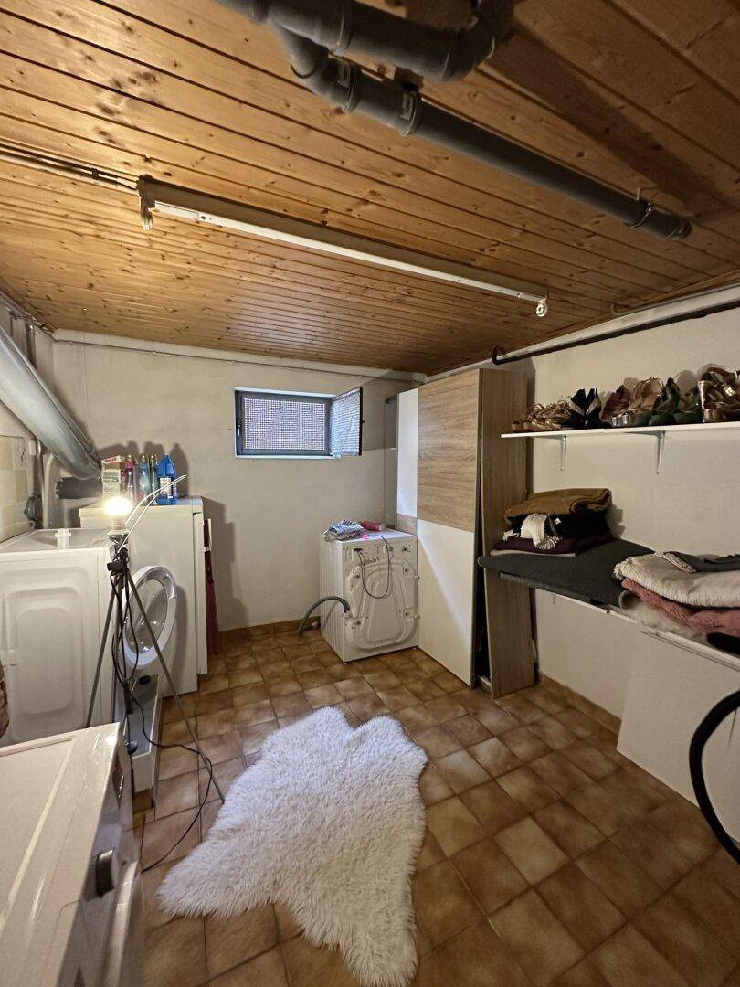 Waschküche im Keller mit Waschmaschinen, Trockner und Stauraum.