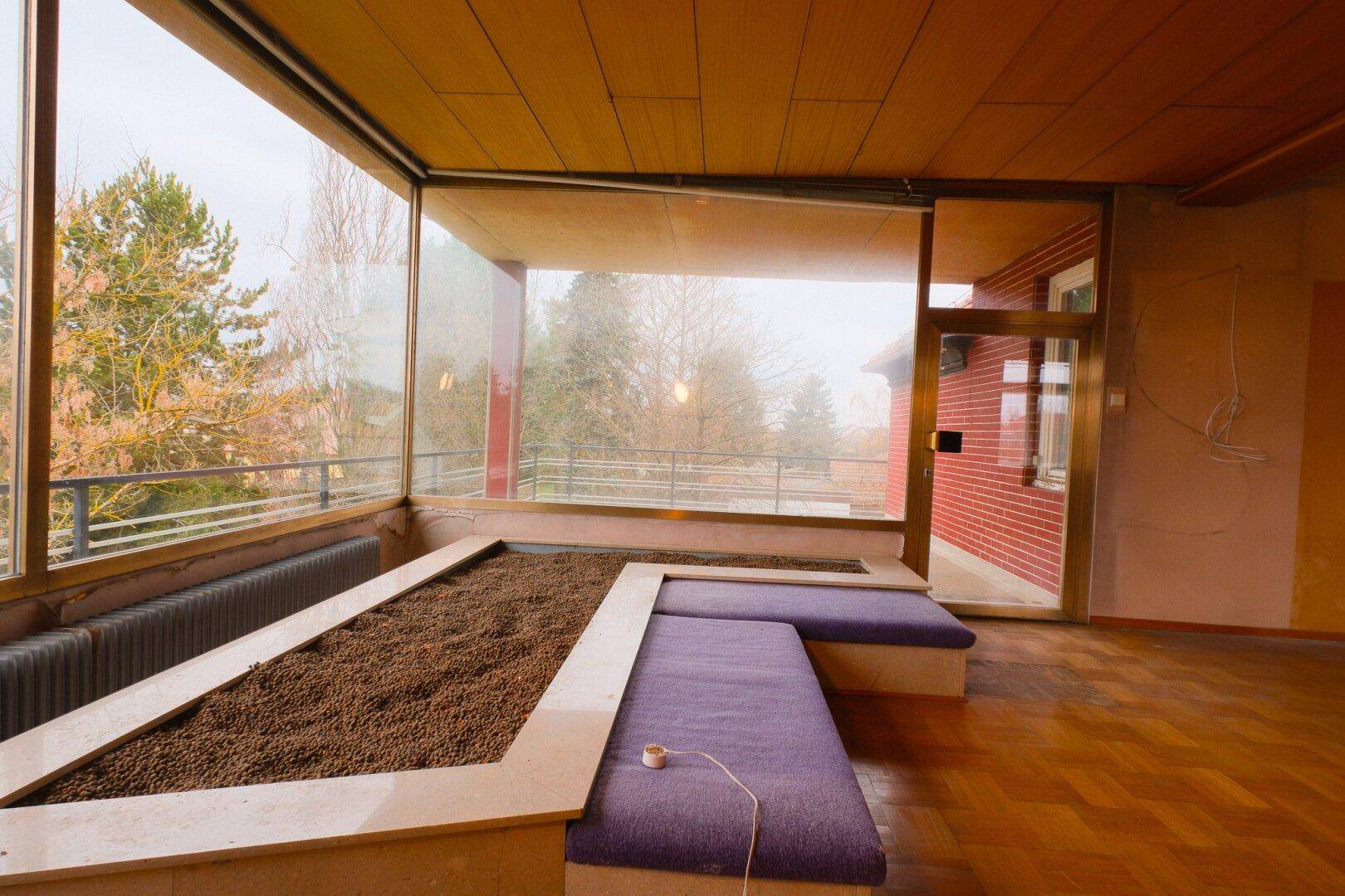 Helles Wohnzimmer mit Panoramafenstern, Parkettboden und integrierten Pflanzbeeten.
