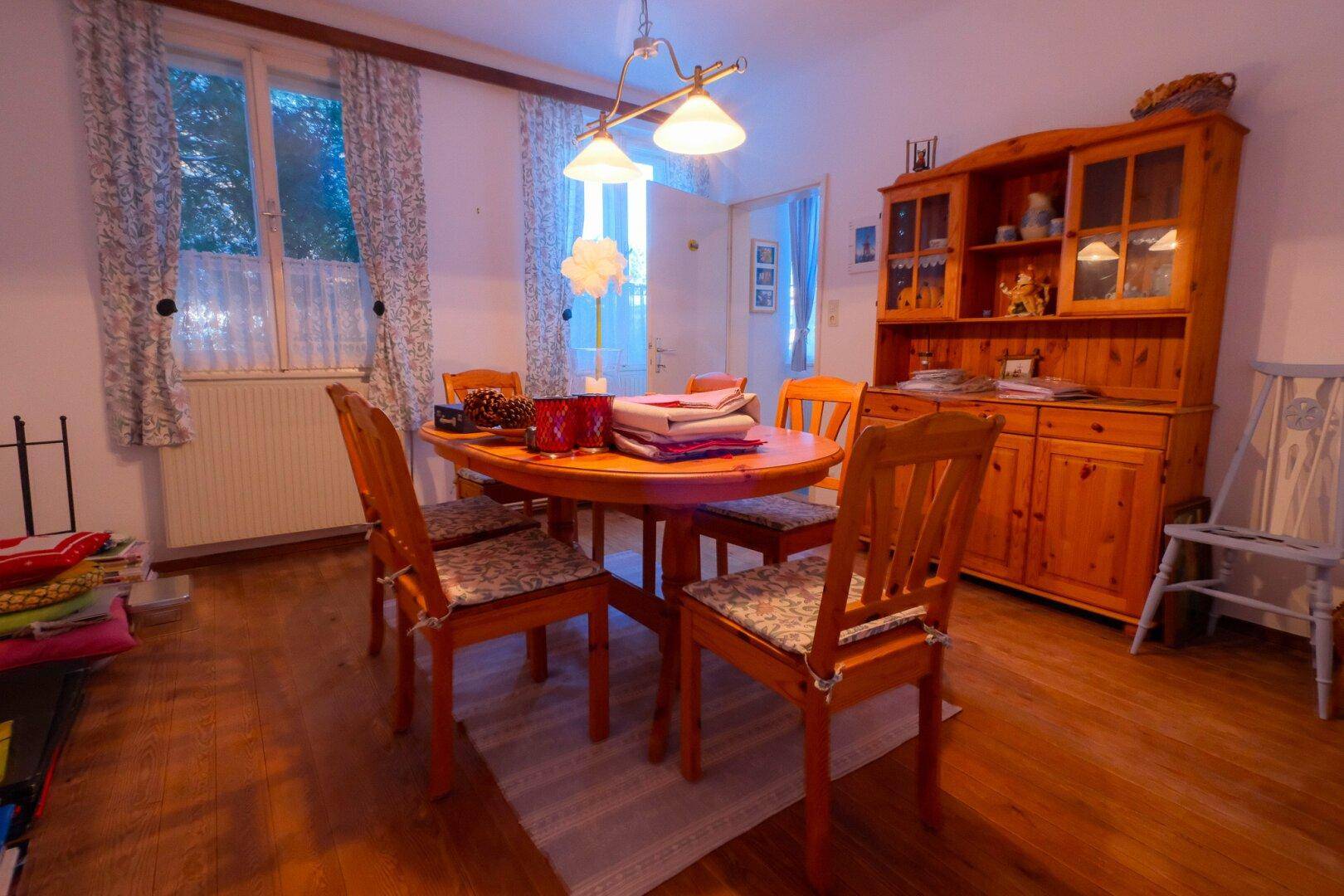 Esszimmer mit traditionellen Holzmöbeln, Esstisch und einem großen Schrank, gut beleuchtet.