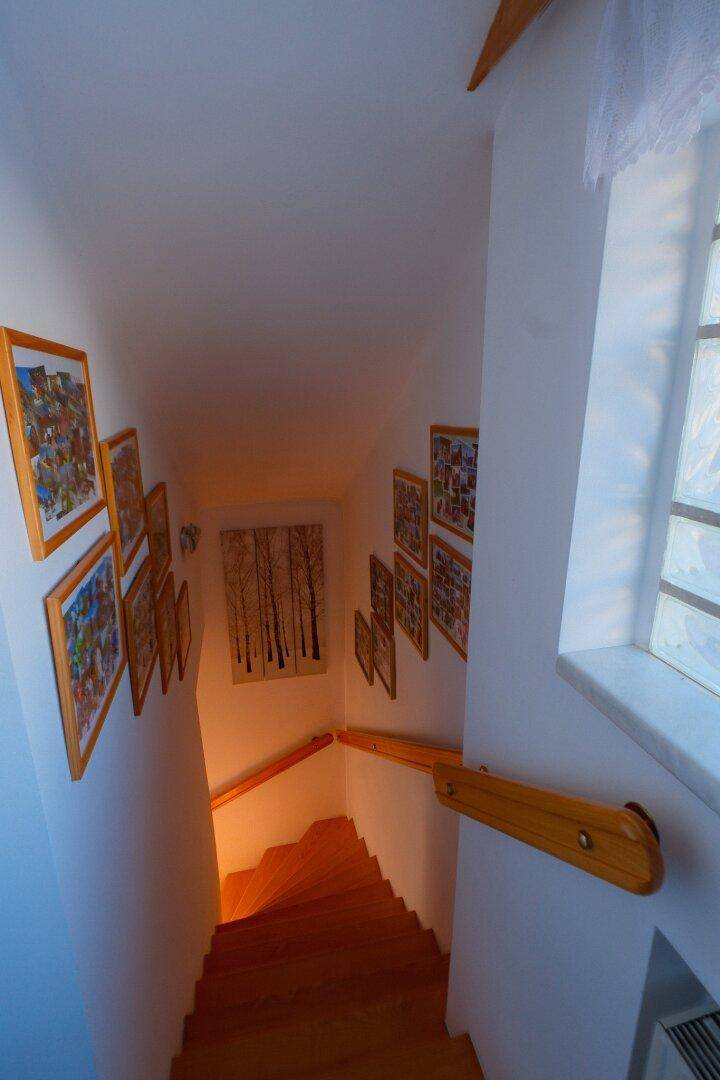 Holztreppe mit Geländer und Wanddekorationen, die in die oberen Etagen führt.