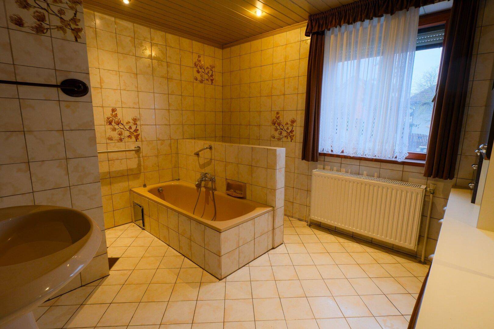 Badezimmer im Stil der 80er Jahre mit beiger Badewanne, Fliesen und Holzdecke.
