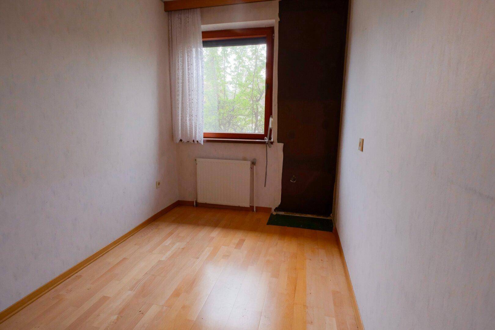 Kleines Zimmer mit Parkettboden und Fenster, ideal als Kinder- oder Gästezimmer.
