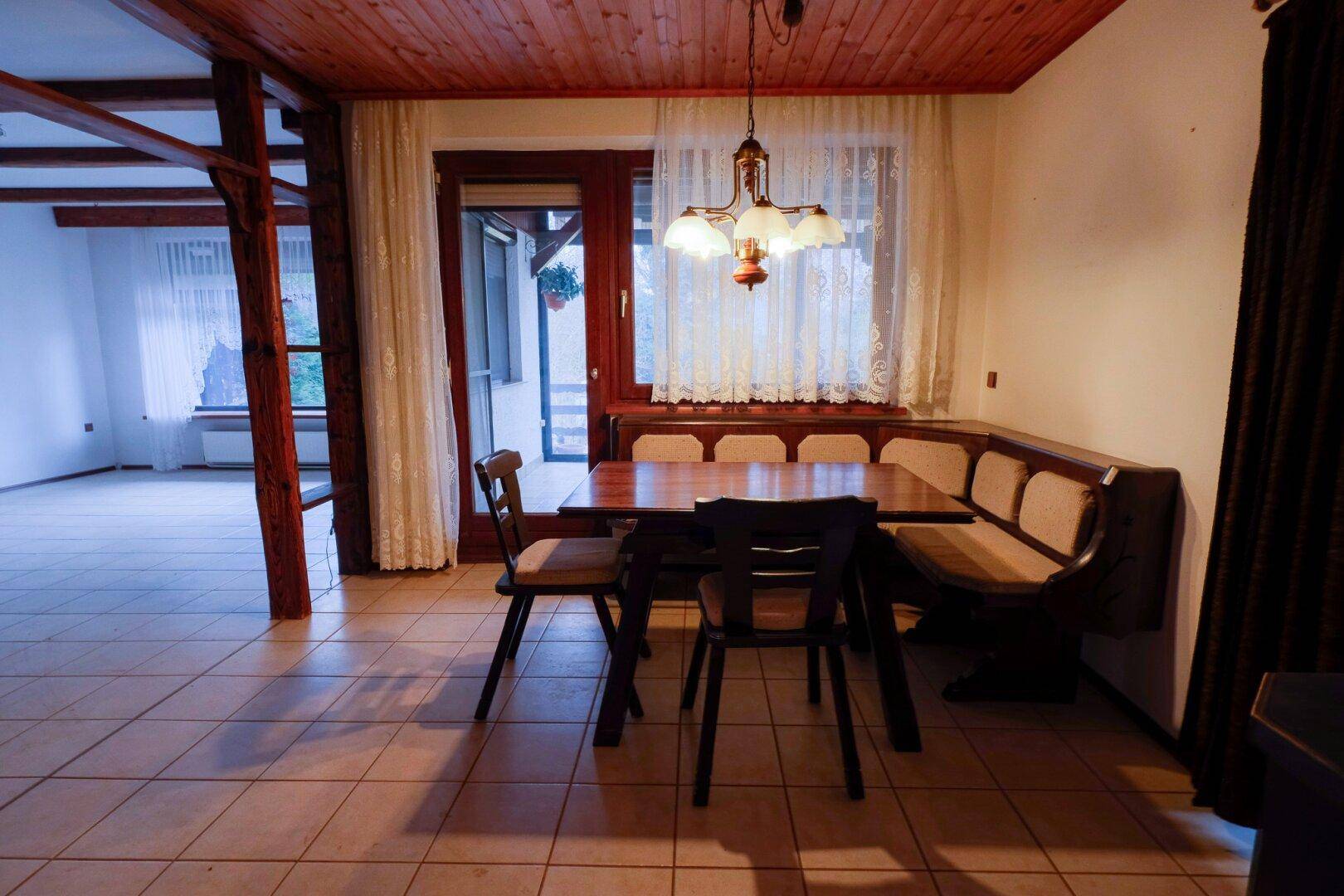 Gemütlicher Essbereich mit Holztisch, Eckbank und Zugang zur Terrasse.
