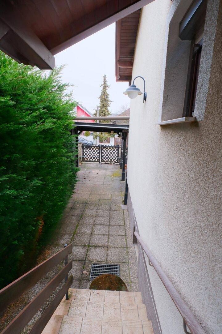 Seitlicher Zugang zum Grundstück mit gepflastertem Weg und Gartentor.