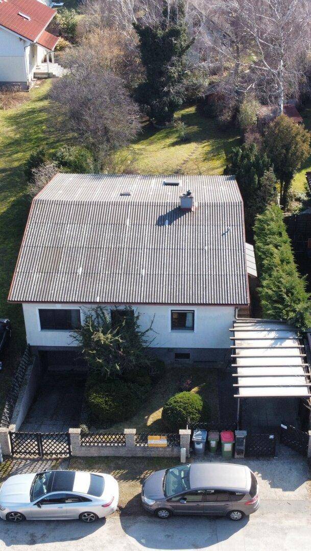 Dachansicht des Hauses mit Wellblechdach, Schornstein und angrenzendem Carport.