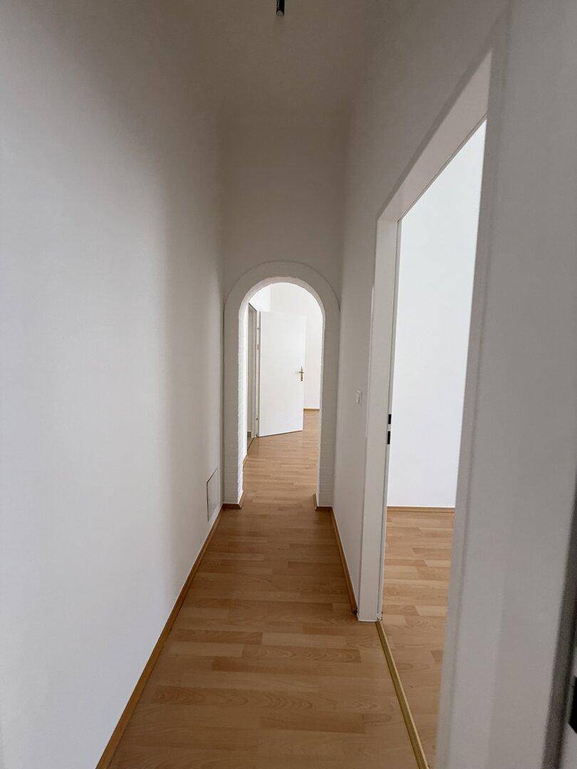 Langer Flur mit Holzfußboden und eleganten Rundbögen, der zu weiteren Räumen führt.