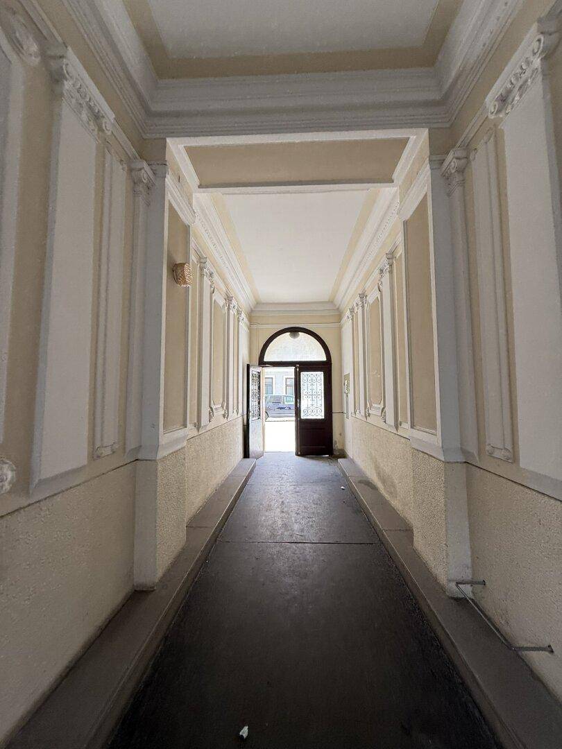 Historischer Eingangsbereich eines Altbaus mit Stuckverzierungen und Blick zur Straße.