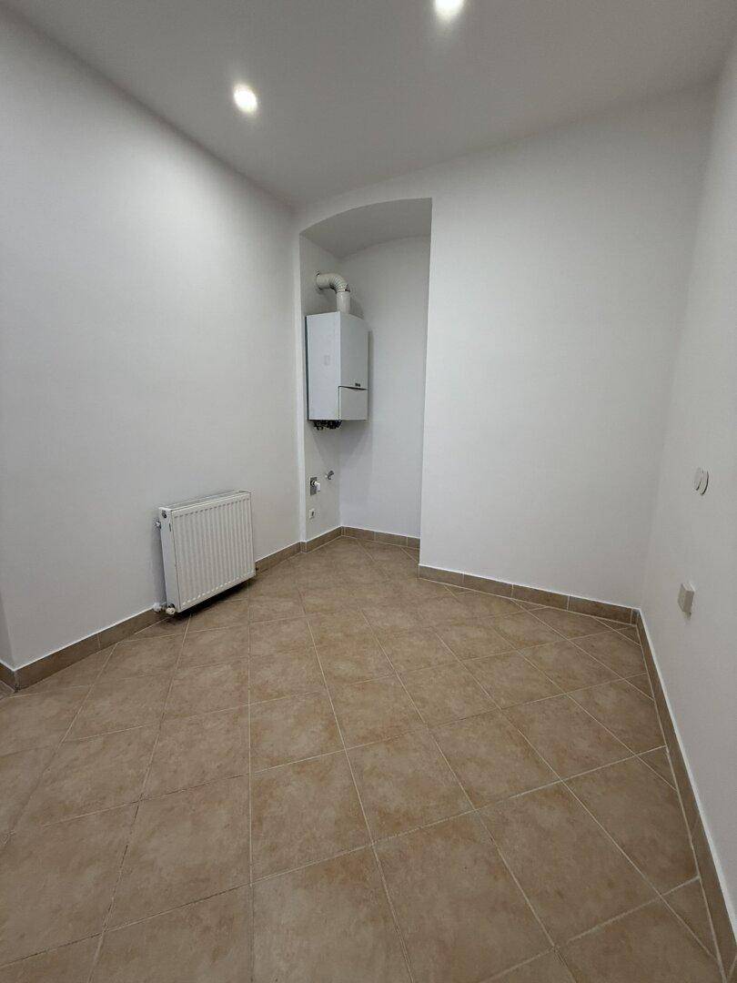 Gefliester Raum mit Heizkörper und Gastherme in einer Nische, geeignet als Hauswirtschaftsraum.
