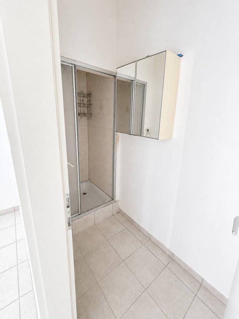 Kleines Badezimmer mit Duschkabine und Spiegelschrank.