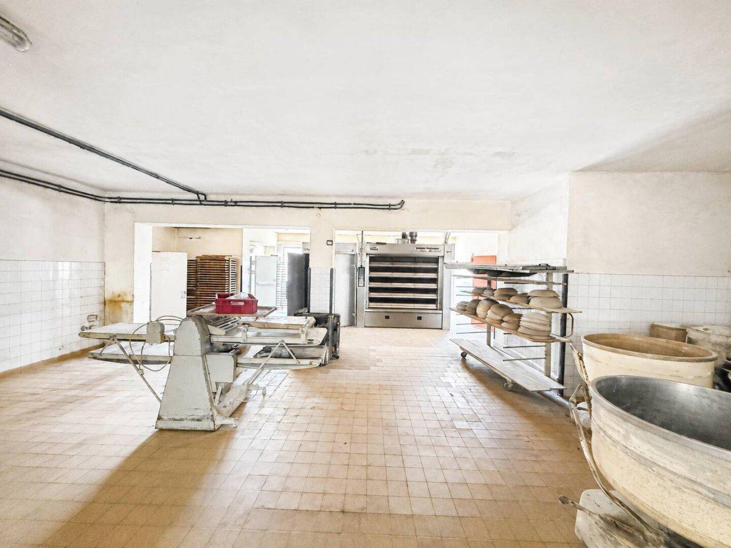 Geräumiger Wirtschaftsraum mit großen Öfen, Arbeitsflächen und Fliesenboden.