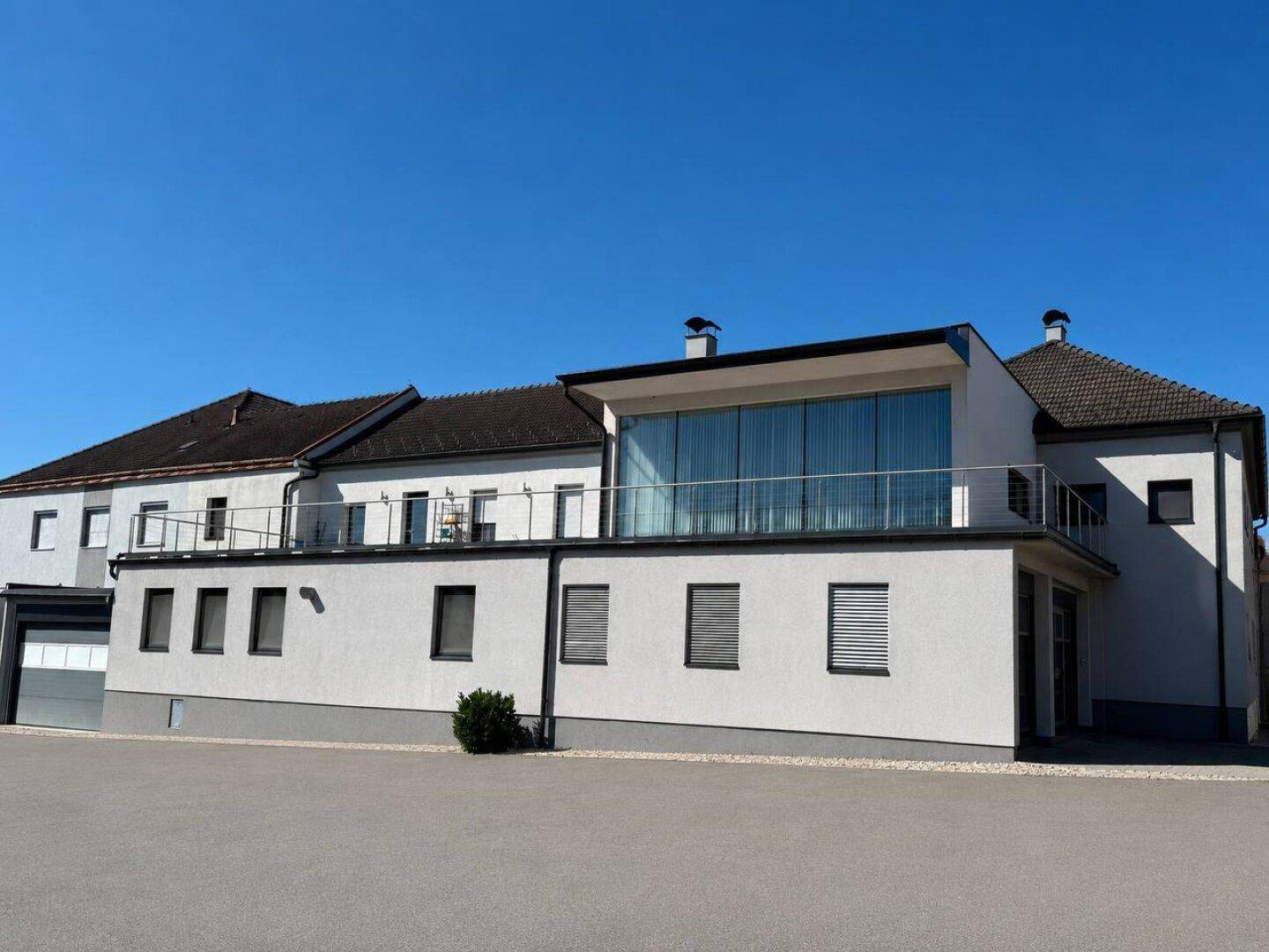 Moderne Architektur mit großen Glasfronten und einer weitläufigen Terrasse am Gebäude.