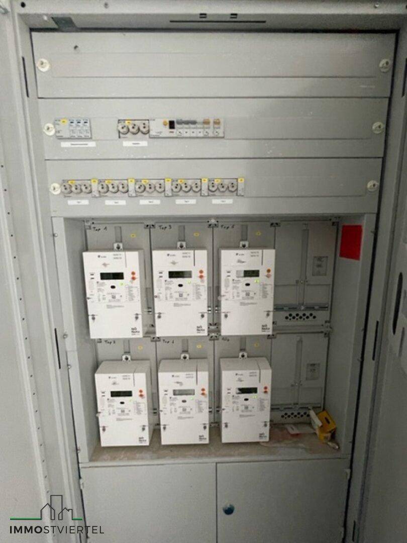 Elektrischer Verteilerkasten mit mehreren Stromzählern und Sicherungen.
